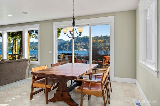 dining space featuring a water view and a notable chandelier