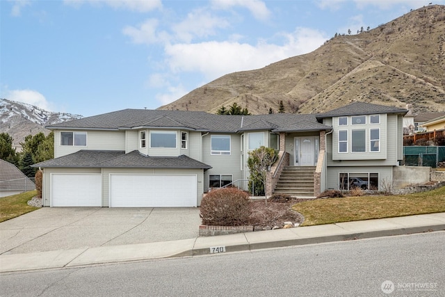 view of front of house featuring a mountain view, driveway, a garage, and roof with shingles