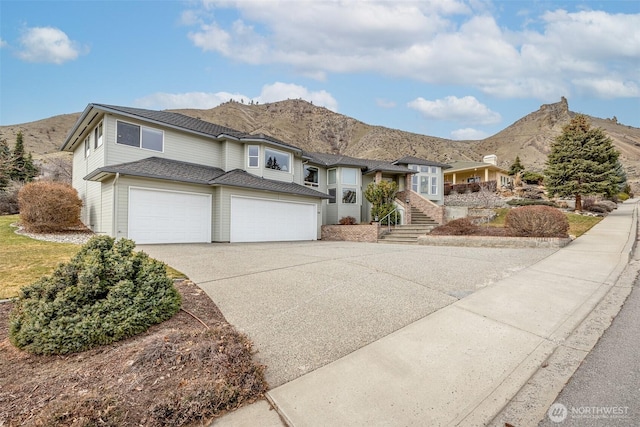 view of front facade featuring stairs, a mountain view, driveway, and an attached garage