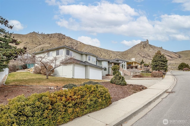 view of front of property with a mountain view, driveway, a garage, and fence