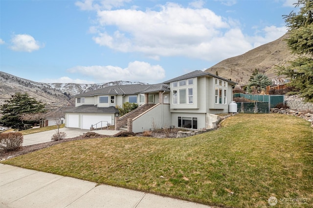 view of front of house with a front lawn, a mountain view, concrete driveway, an attached garage, and stairs