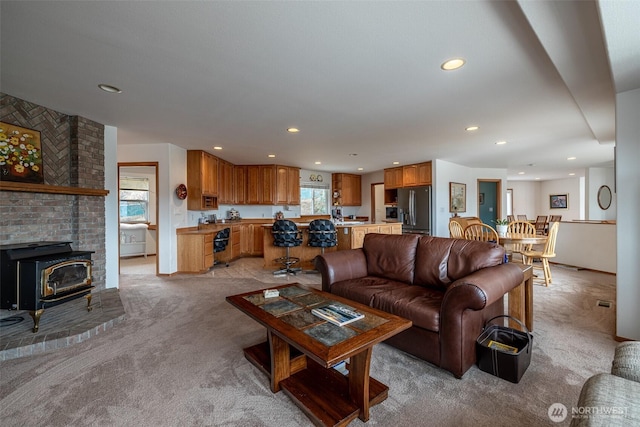 living area featuring a wood stove, recessed lighting, and light colored carpet