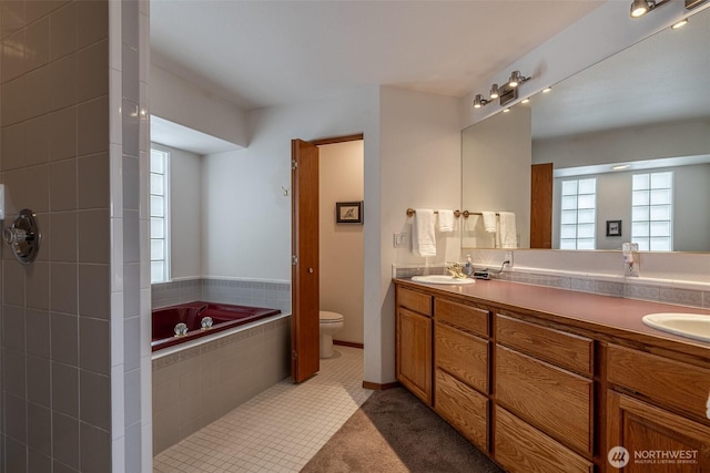 full bath featuring a sink, toilet, a garden tub, and double vanity