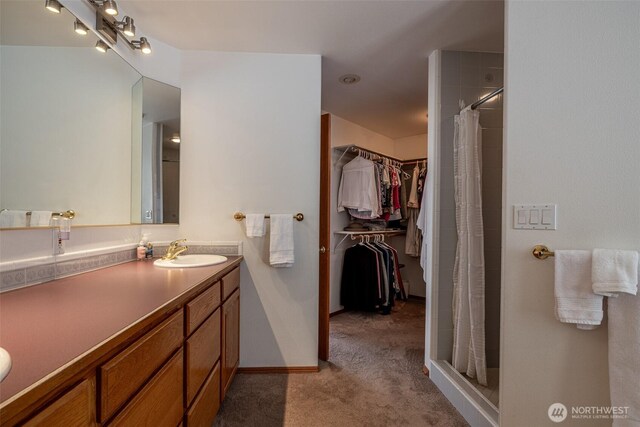 bathroom with vanity, a spacious closet, baseboards, and a stall shower