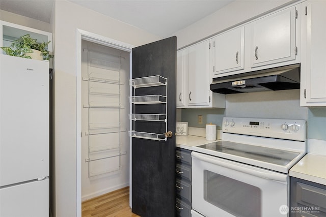 kitchen with white appliances, white cabinets, light countertops, light wood-type flooring, and under cabinet range hood