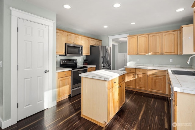 kitchen featuring stainless steel appliances, a kitchen island, sink, and tile counters