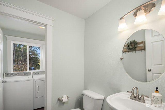 bathroom featuring sink, washer and clothes dryer, and toilet