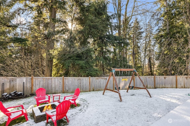 snow covered patio with a playground and an outdoor fire pit