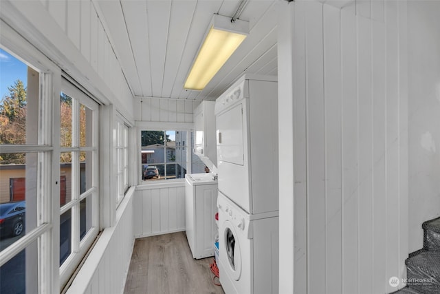 laundry room with stacked washing maching and dryer and light wood-type flooring