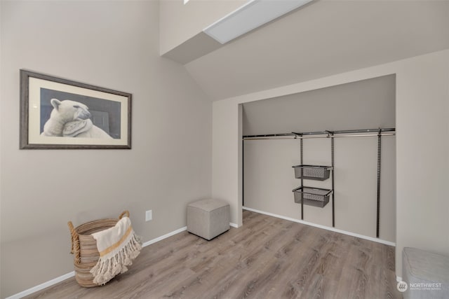 unfurnished bedroom featuring vaulted ceiling, a closet, and light wood-type flooring