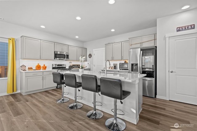 kitchen featuring stainless steel appliances, sink, a breakfast bar, and a center island with sink