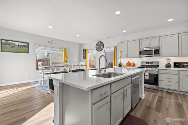 kitchen with gray cabinets, an island with sink, appliances with stainless steel finishes, and sink