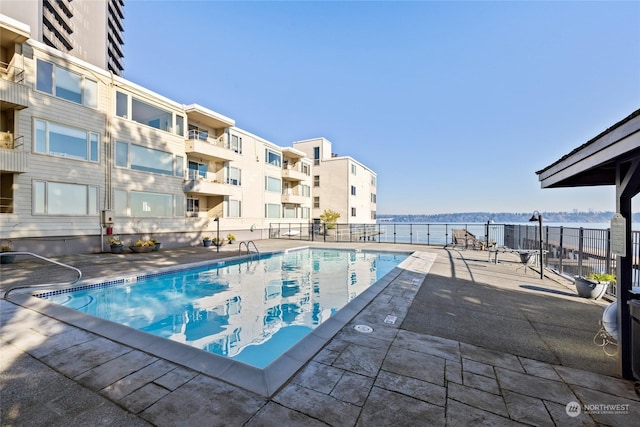 view of swimming pool featuring a patio and a water view