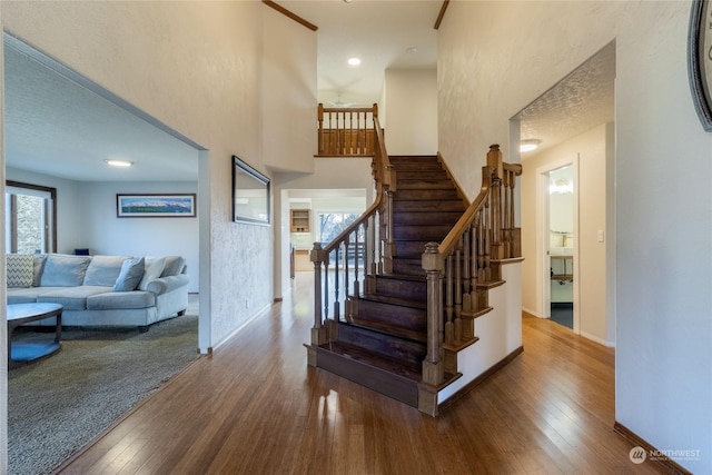 stairway with hardwood / wood-style flooring and a towering ceiling