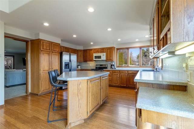 kitchen featuring a breakfast bar, sink, light wood-type flooring, a kitchen island, and stainless steel appliances