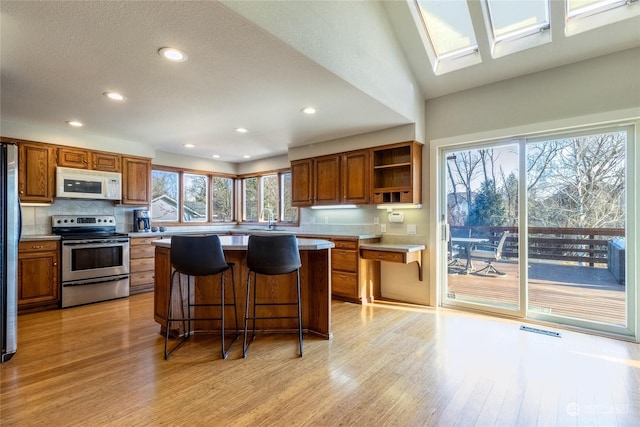 kitchen with light hardwood / wood-style flooring, stainless steel appliances, a center island, and a kitchen bar