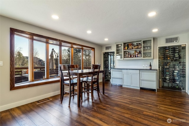 dining room with dark wood-type flooring, bar, and beverage cooler