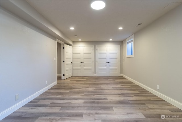 unfurnished bedroom with two closets and light wood-type flooring