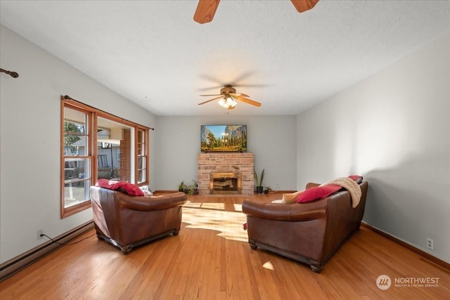 living room featuring ceiling fan, wood-type flooring, a fireplace, and a baseboard radiator