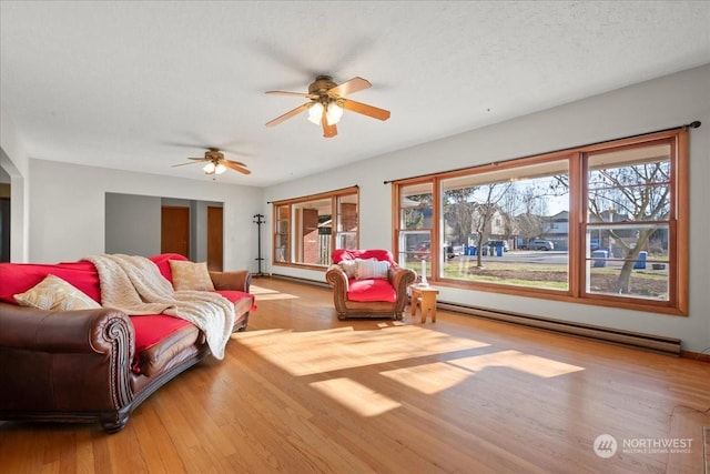 living room with ceiling fan, light wood-type flooring, a textured ceiling, and a baseboard heating unit