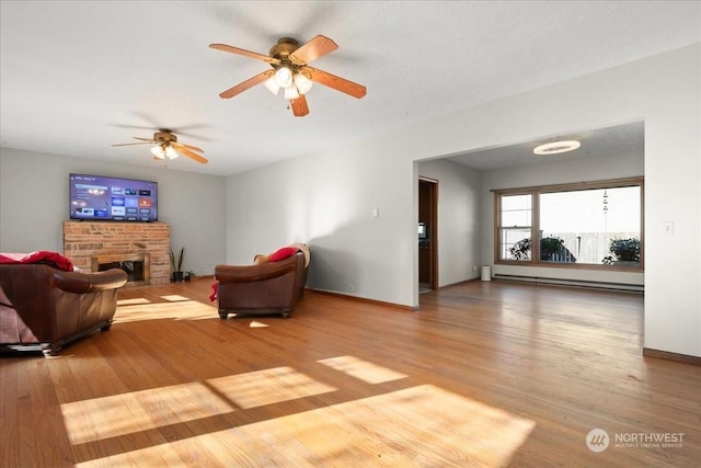 living room featuring a baseboard heating unit, light hardwood / wood-style flooring, and a fireplace