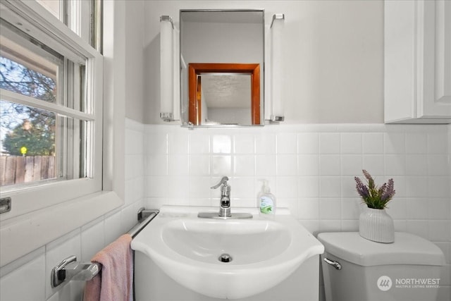 bathroom featuring sink, tile walls, and toilet