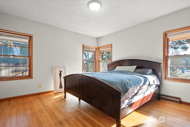 bedroom featuring a baseboard radiator, light hardwood / wood-style flooring, and a textured ceiling