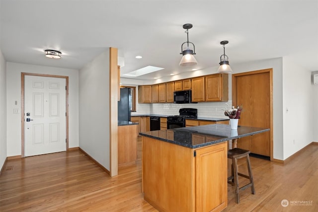 kitchen featuring a breakfast bar area, hanging light fixtures, a skylight, black appliances, and a kitchen island