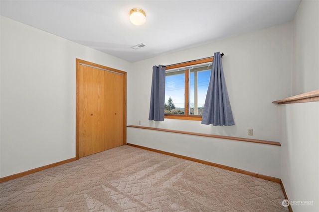 unfurnished bedroom with light colored carpet and a closet