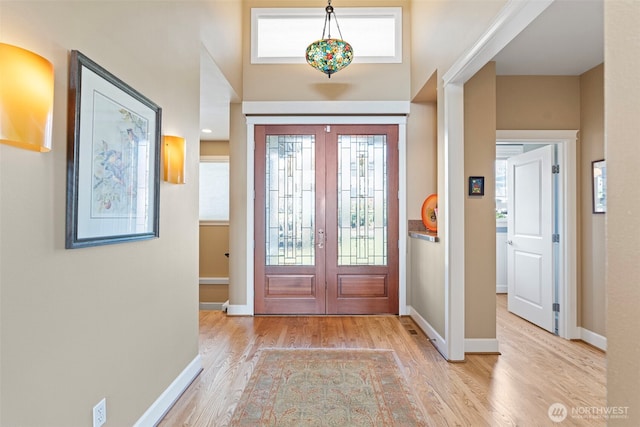 foyer entrance featuring light wood-type flooring, french doors, and plenty of natural light