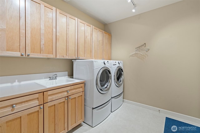 washroom featuring a sink, baseboards, washer and dryer, cabinet space, and track lighting