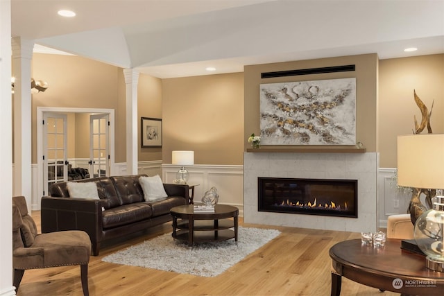 living room featuring a fireplace, wood-type flooring, and decorative columns