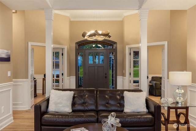 living room featuring decorative columns, ornamental molding, and light hardwood / wood-style floors