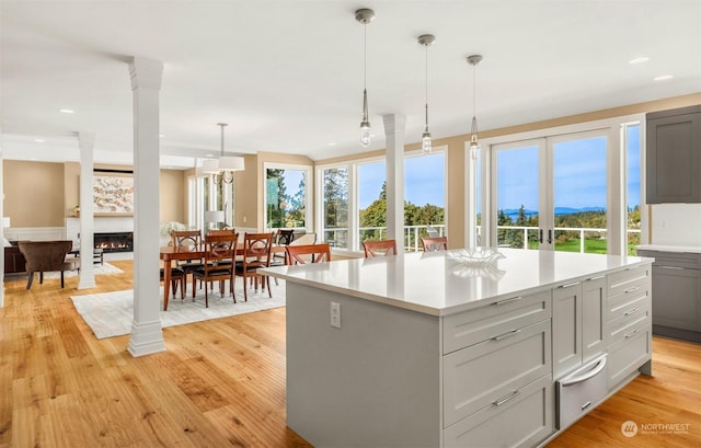 kitchen with gray cabinets, a kitchen island, decorative columns, and decorative light fixtures