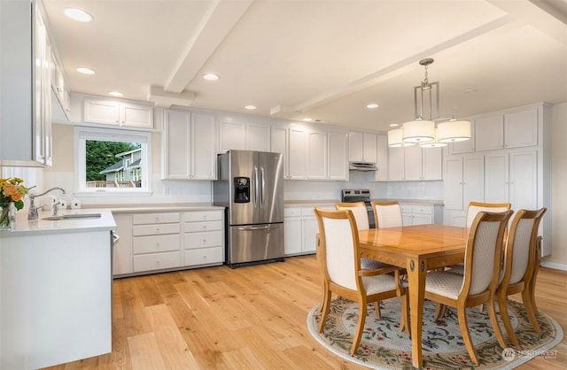 kitchen featuring appliances with stainless steel finishes, decorative light fixtures, white cabinetry, sink, and light wood-type flooring