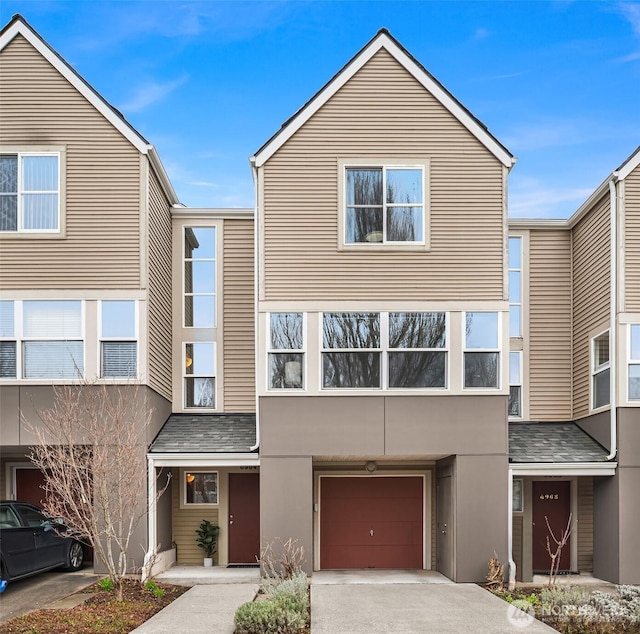 townhome / multi-family property featuring roof with shingles, a garage, driveway, and stucco siding