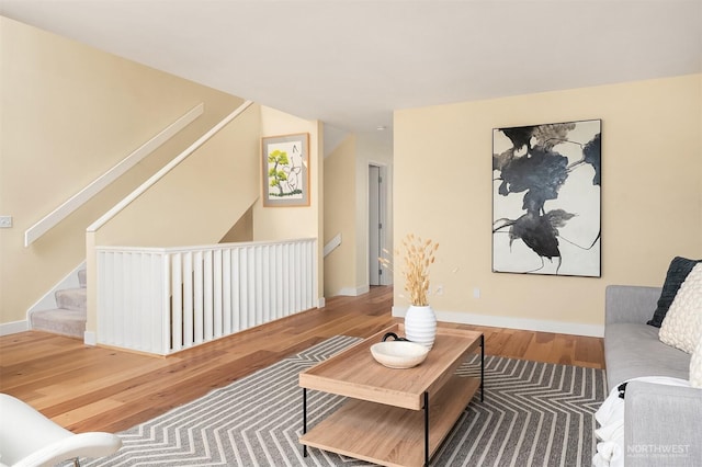 living room with stairs, baseboards, and wood finished floors