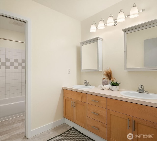 full bathroom featuring double vanity, baseboards, and a sink