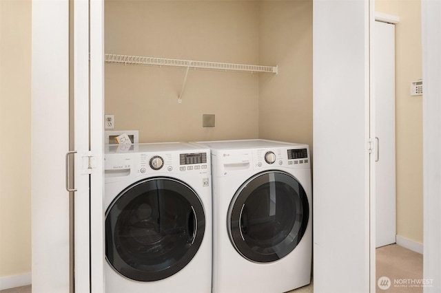 laundry area with laundry area, washer and dryer, and baseboards