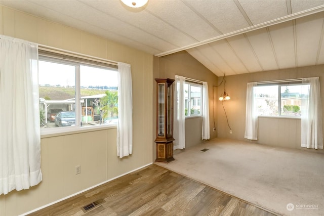 unfurnished room with hardwood / wood-style floors and vaulted ceiling