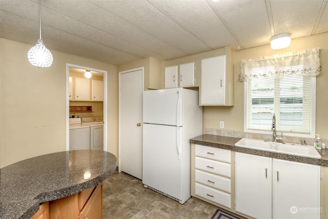 kitchen with sink, washer and clothes dryer, white cabinetry, decorative light fixtures, and white fridge