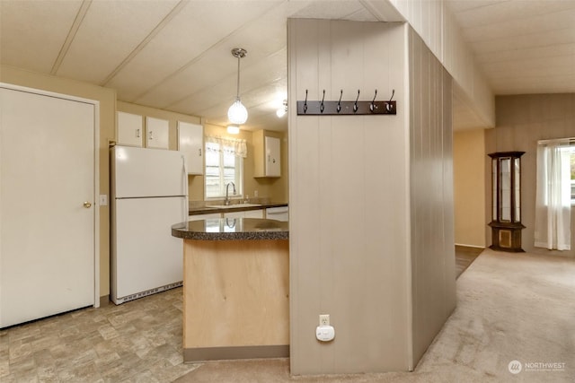 kitchen featuring pendant lighting, sink, light colored carpet, kitchen peninsula, and white appliances