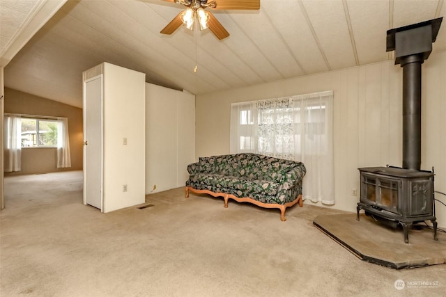 sitting room featuring ceiling fan, lofted ceiling, light carpet, and a wood stove