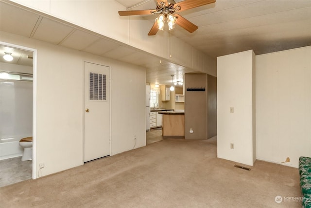 unfurnished living room with ceiling fan, light colored carpet, and sink