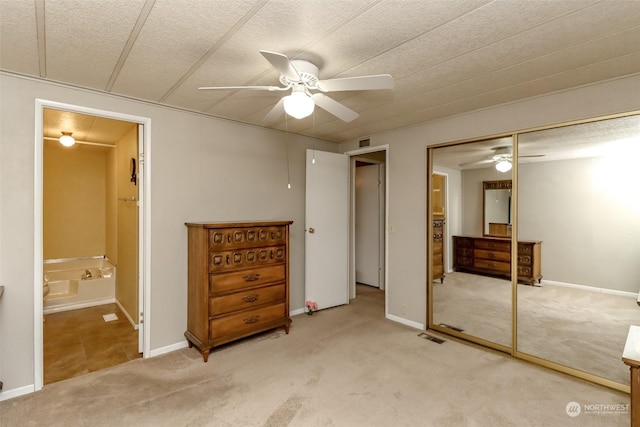 bedroom featuring ensuite bathroom, light colored carpet, ceiling fan, a textured ceiling, and a closet