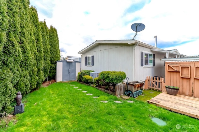 rear view of property with a storage shed, a deck, and a lawn