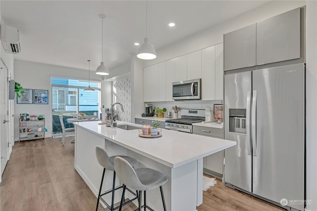 kitchen with pendant lighting, sink, appliances with stainless steel finishes, a kitchen breakfast bar, and a center island with sink