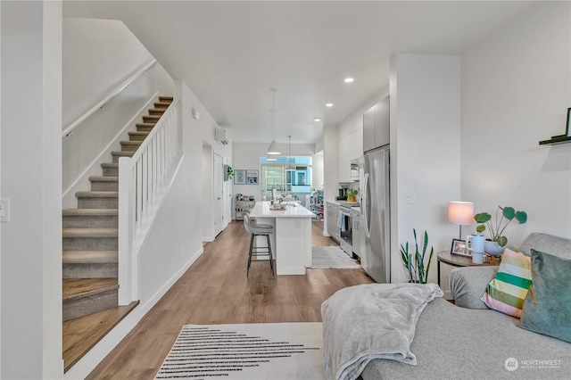 living room featuring sink, a wall unit AC, and light wood-type flooring