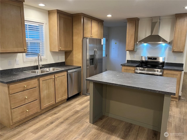 kitchen with a kitchen island, sink, stainless steel appliances, wall chimney range hood, and light hardwood / wood-style flooring