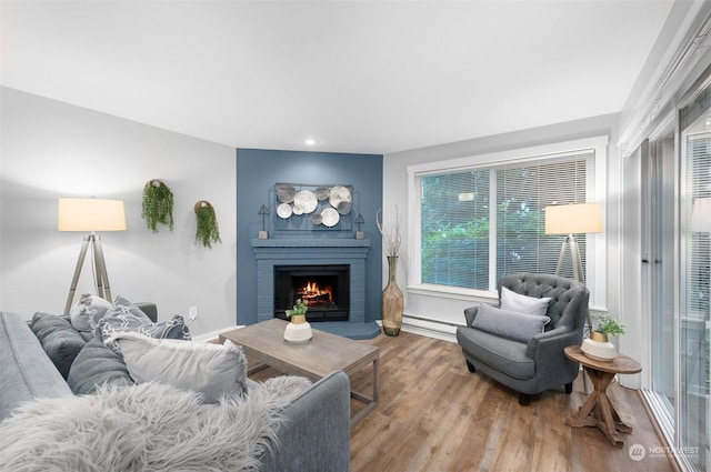 living room with a baseboard heating unit, hardwood / wood-style floors, and a fireplace